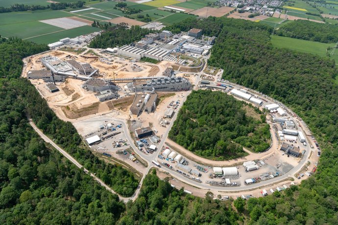 A large construction site is surrounded by forest.