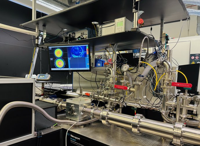 A complex measurement setup consisting of silver tubes, cables and a screen is located on a table.