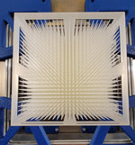 In einem blauen Metallrahmen ist ein weißes, rechteckiges Objekt mit vielen nach vorn ragenden Spitzen montiert.