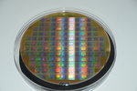 Silicon wafer with circuits designed by a GSI/FAIR developing team. Eine runde Scheibe mit Mikrochips schillert in bunten Farben.
