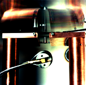 Detail: Tantalum crucible below the evaporation wheel with quartz sensor in front On this picture you see a detailed view. A tantalum crucible is located directly below the evaporation wheel. In front you see a quartz crystal sensor for measuring the evaporation rate.