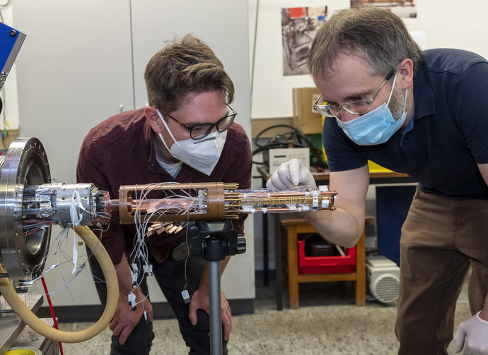 Matthew Bohman (links) und Dr. Christian Smorra installieren die neue Falle in die Apparatur.