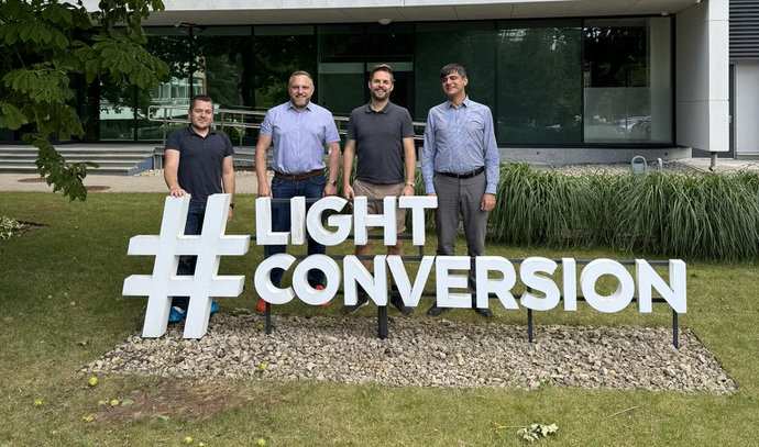Vier Männer stehen auf einer grünen Wiese vor einem Gebäude und hinter der Aufschrift "Light Conversion". Vier Männer stehen auf einer grünen Wiese vor einem Gebäude und hinter der Aufschrift "Light Conversion".