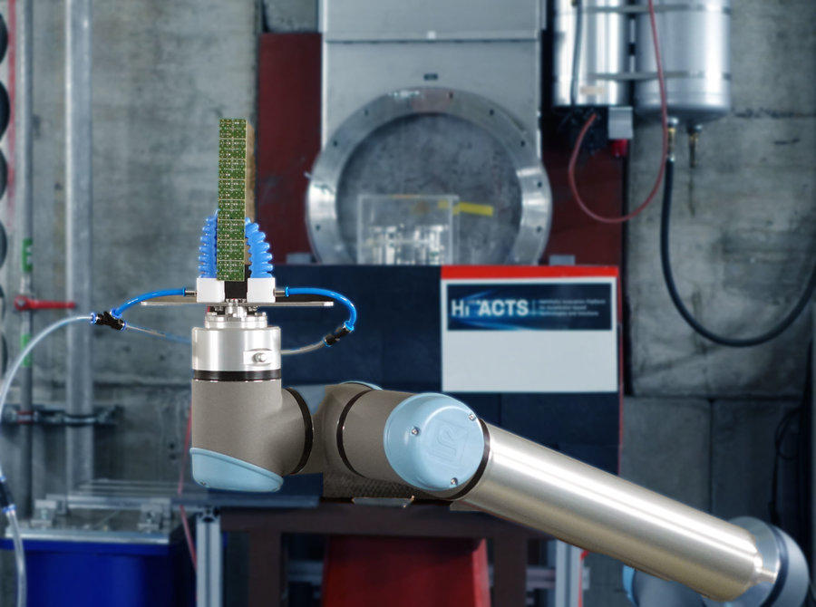 Standardisierte Station für Hochenergie-Ionenbestrahlung von Elektronik bei GSI Ein Roboterarm hält eine Materialprobe vor den Ionenstrahl