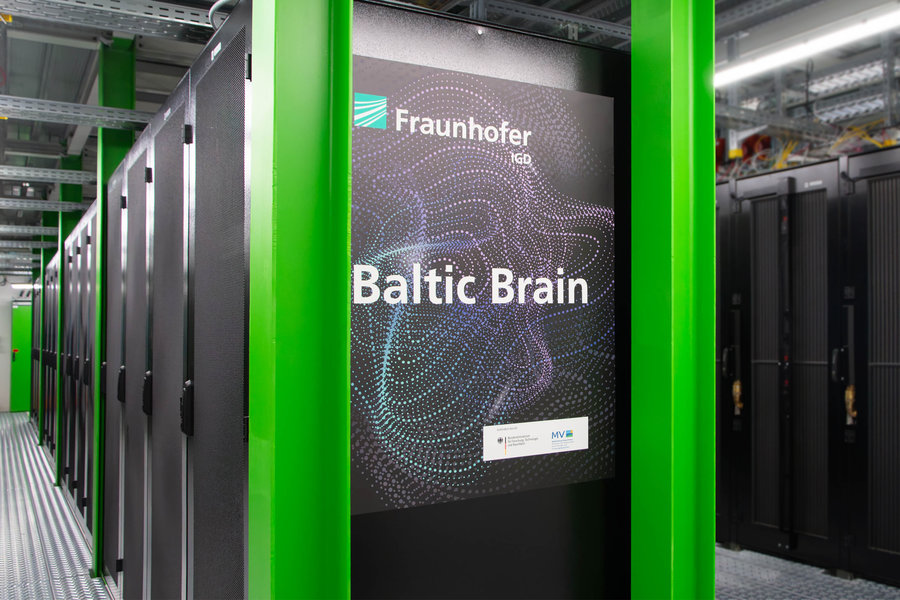 Der GPU-Cluster „Baltic Brain“ des Fraunhofer IGD wird im Green IT Cube von GS/FAIR betrieben Eine Reihe von schwarzen Rechnerschränken ist in einem Gerüst von grünen Metallträgern aufgestellt. Am Kopfende prangt ein Aufkleber mit der Aufschrift "Baltic Brain".