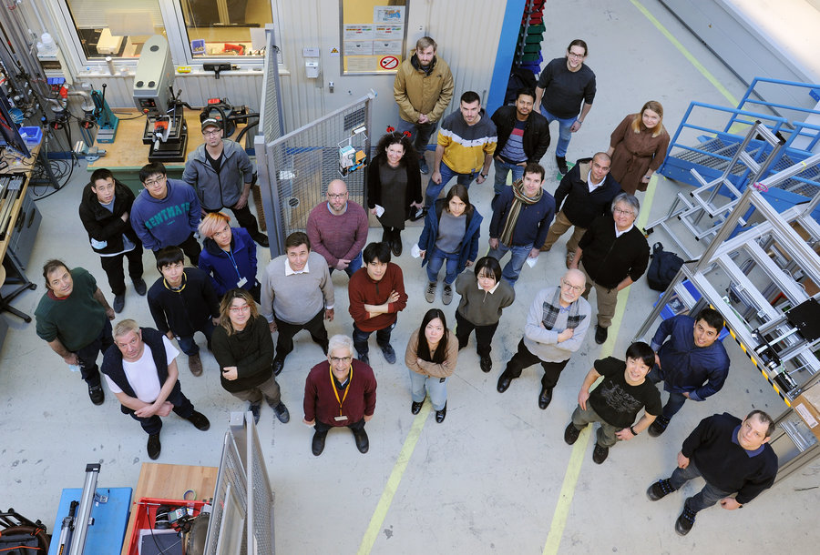 Part of the research team participating in the successful experiment Eine von oben fotografierte Personengruppe steht vor einem Messcontainer.
