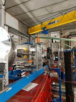 Im Vordergrund links ist das Strahlrohr sichtbar, gefolgt von Strahlmonitoren (silberne Kammer mit goldener Folie). Im Hintergrund befindet sich die Elektronikteststation mit der montierten Nikon-Z9-Kamera, welche die NASA bei GSI/FAIR getestet hat. Die Kamera (Display ist angeschaltet und sichtbar) ist zur rechten Seite aus dem Strahlweg herausgefahren.